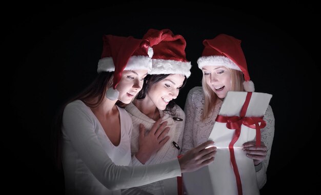 Grupo de estudantes do sexo feminino em trajes de Papai Noel abrindo ab