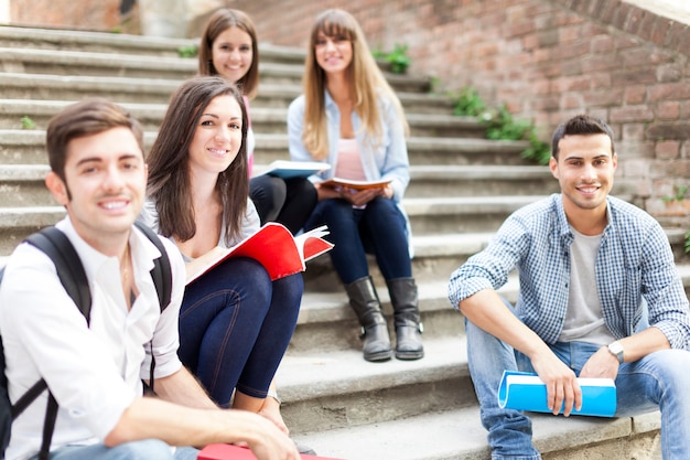 Grupo de estudantes sorridentes, sentado em uma escada