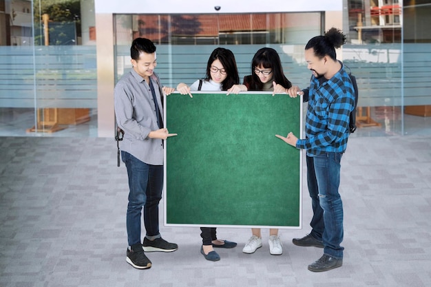 Grupo de estudantes universitários apontando para o quadro verde com espaço de cópia