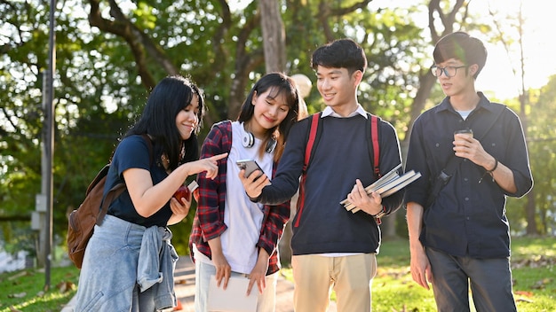 Grupo de estudantes universitários asiáticos felizes gostam de conversar e caminhar juntos no parque do campus