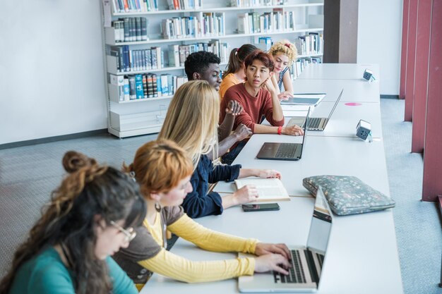 Grupo de estudantes universitários que estudam na universidade se concentram no jovem asiático