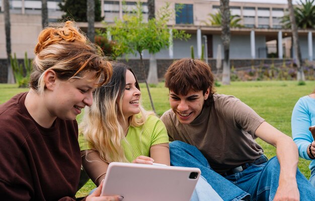 Grupo de estudantes universitários usando tablets na grama do campus