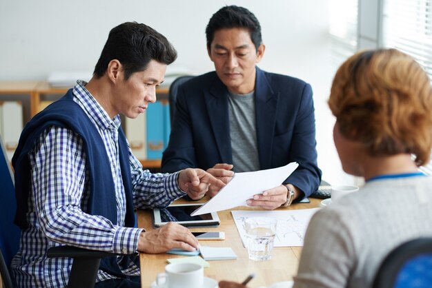 Grupo de executivos sérios discutindo novas ideias durante as sessões de briefing e trabalhando na estratégia de desenvolvimento