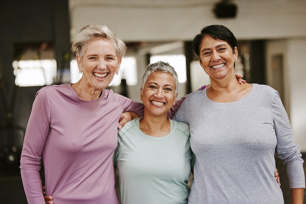 Foto grupo de exercícios de mulheres idosas e retrato com sorriso de abraço e apoio ao objetivo de bem-estar mulheres idosas em equipe e felicidade na academia para solidariedade de amigos ou diversidade para motivação do trabalho em equipe