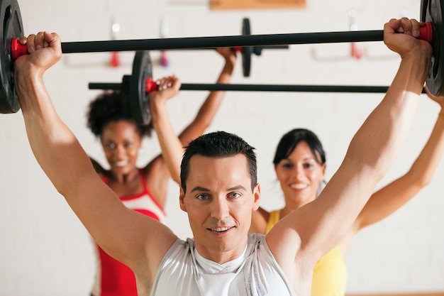 Foto grupo de fitness com barra no ginásio