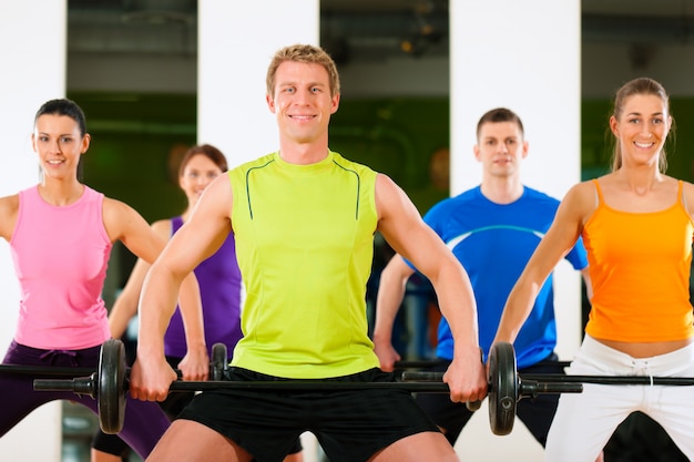 Foto grupo de fitness com barra no ginásio