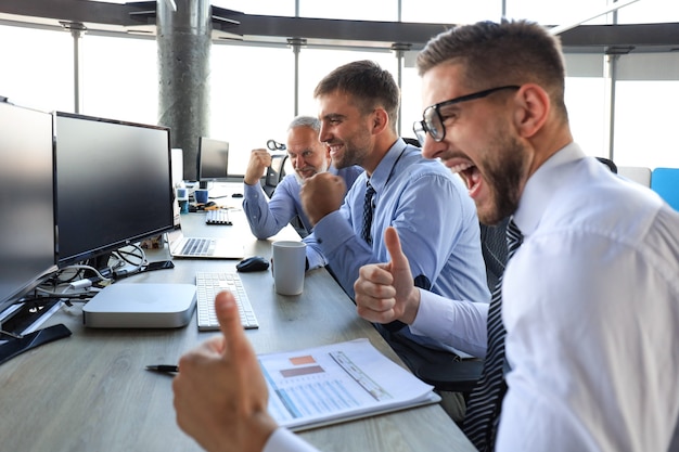 Grupo de homens de negócios modernos em trajes formais, sorrindo e gesticulando enquanto trabalhava no escritório.