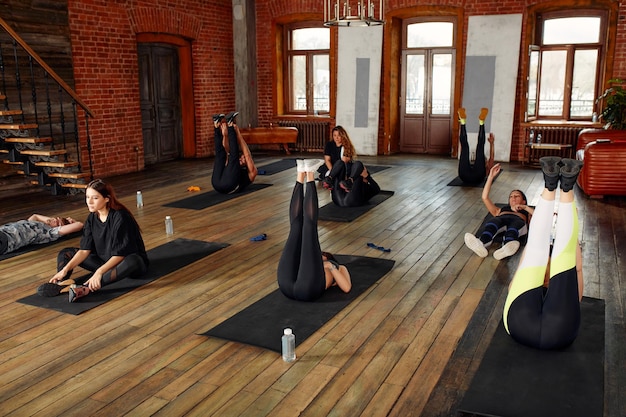 Foto grupo de homens e mulheres atléticos adultos realizando exercícios abdominais para fortalecer seus músculos abdominais centrais no treinamento físico