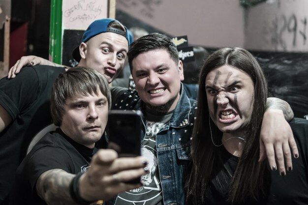 Grupo de homens faz selfie em um quarto escuro, fazendo careta diante da câmera