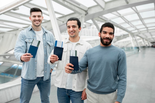 Grupo de homens mostrando cartões de embarque em pé no aeroporto moderno