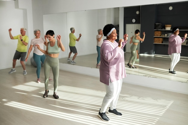 Grupo de idosos dançando no health club junto com o treinador