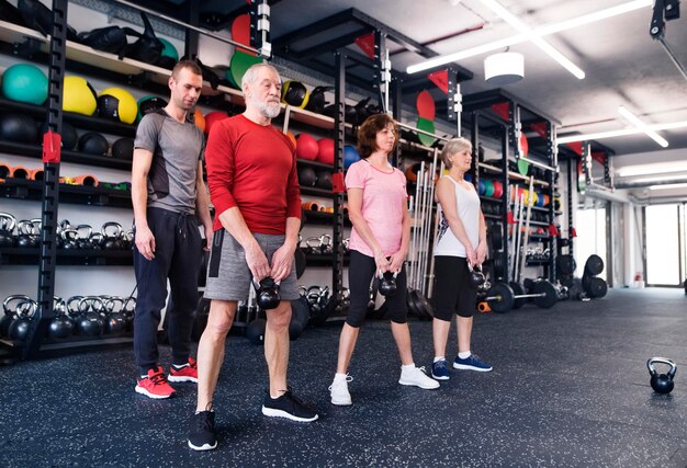 Grupo de idosos em forma com personal trainer na academia