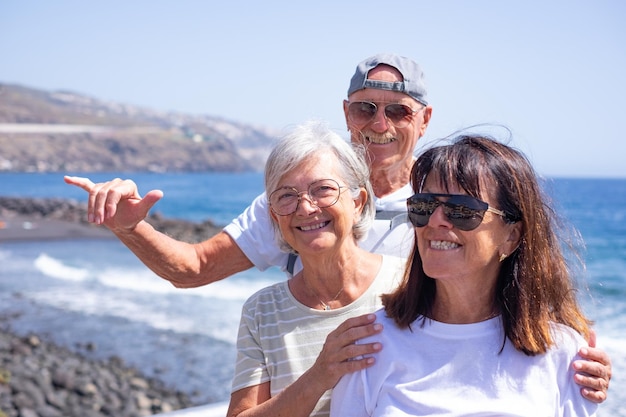 Grupo de idosos felizes parados perto da praia aproveitando as férias no mar e a liberdade