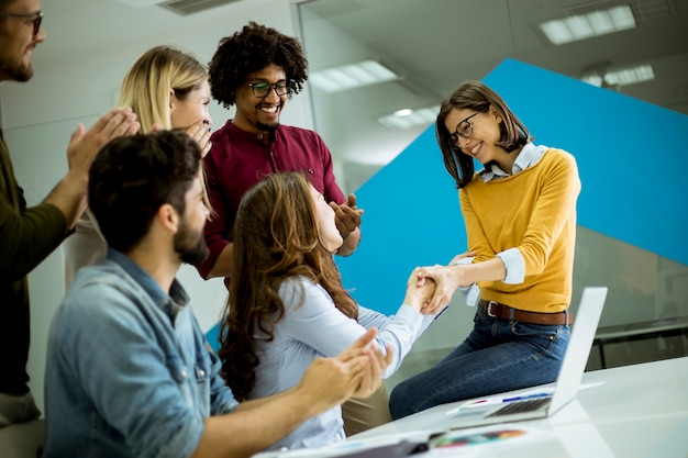 Foto grupo, de, jovem, colegas trabalho, interação, ao redor, um, tabela, e, handshaking, em, escritório