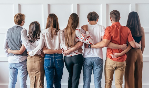 Grupo de jovens abraçando juntos vista traseira