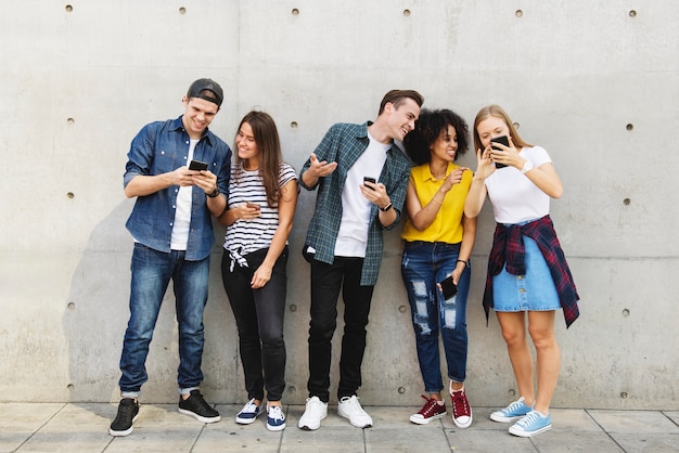 Foto grupo de jovens adultos ao ar livre usando smartphones juntos e refrigeração