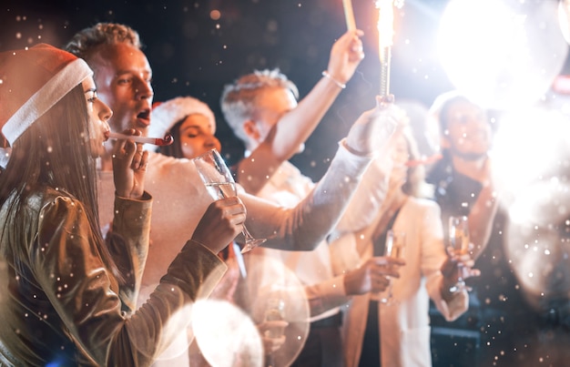 Grupo de jovens alegres tem festa e comemorando o ano novo dentro de casa.