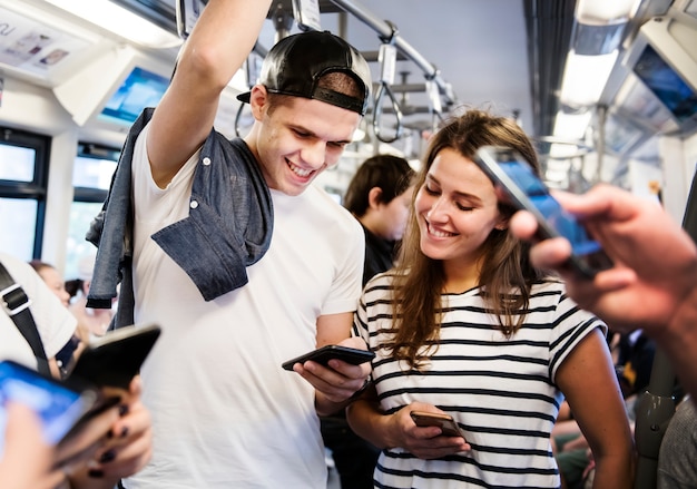 Grupo de jovens amigos adultos usando smartphones no metrô