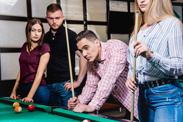 Grupo de jovens amigos alegres jogando bilhar.