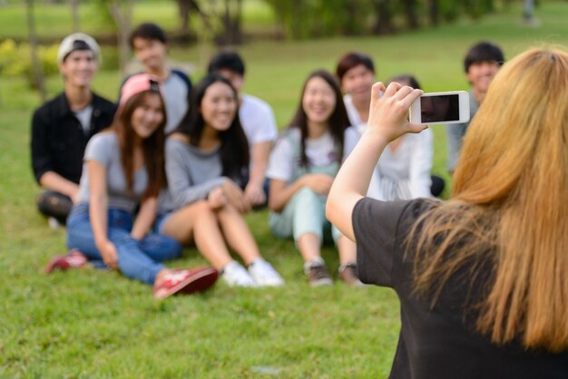 Grupo de jovens amigos asiáticos relaxando juntos no parque ao ar livre