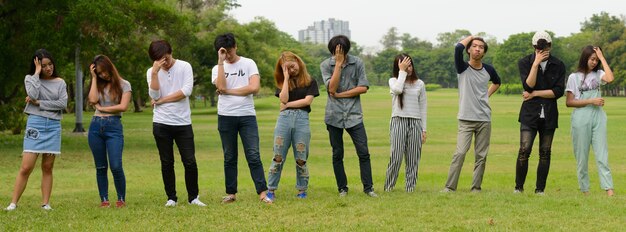 Grupo de jovens amigos asiáticos relaxando juntos no parque ao ar livre