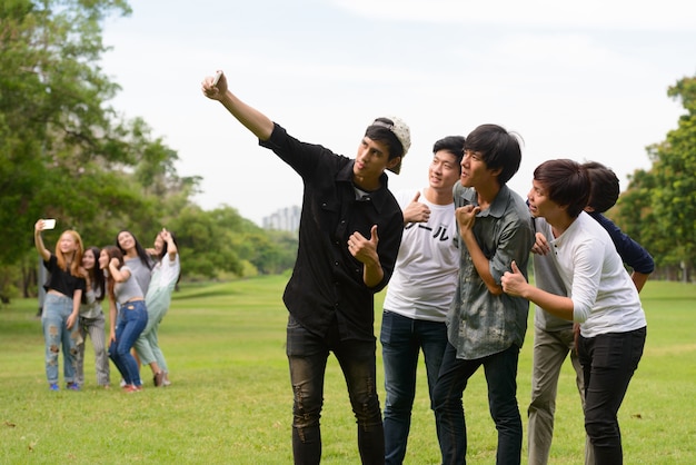 Grupo de jovens amigos asiáticos relaxando juntos no parque ao ar livre