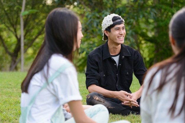Grupo de jovens amigos asiáticos relaxando juntos no parque ao ar livre