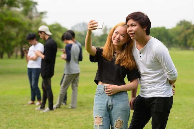 Grupo de jovens amigos asiáticos relaxando juntos no parque ao ar livre