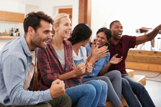 Grupo de jovens amigos assistindo esportes na televisão e torcendo