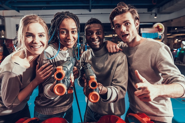 Grupo de jovens amigos atirando armas no arcade.