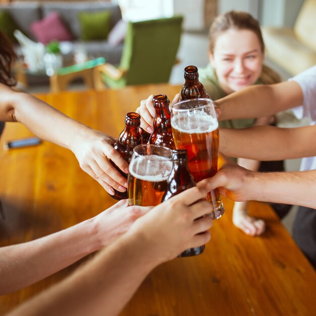 Grupo de jovens amigos bebendo cerveja, se divertindo, rindo e comemorando juntos.