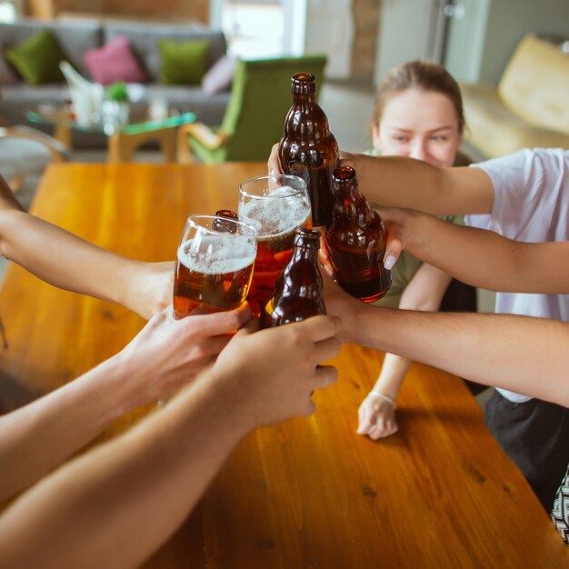 Grupo de jovens amigos bebendo cerveja, se divertindo, rindo e comemorando juntos.