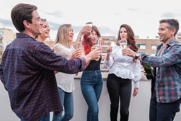 Grupo de jovens amigos brindando no terraço de sua casa ao ar livre e felizes