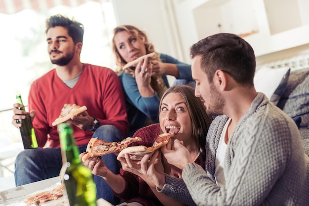 Grupo de jovens amigos comendo pizza saborosa em casa