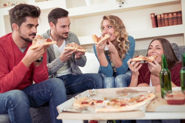Grupo de jovens amigos comendo pizzaFesta em casa