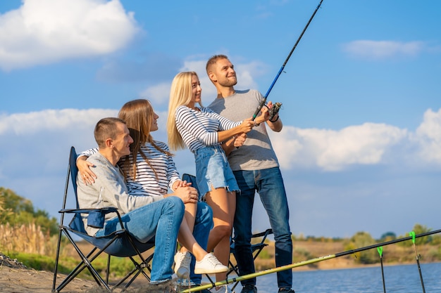 Grupo de jovens amigos de pesca no cais à beira do lago