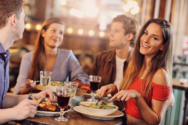 Foto grupo de jovens amigos desfrutando de uma refeição no restaurante