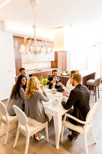 Grupo de jovens amigos jantando em casa e brindar com vinho branco