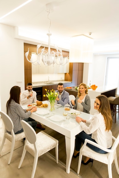 Grupo de jovens amigos jantando em casa e brindar com vinho branco