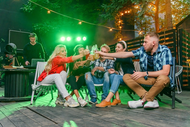 Grupo de jovens amigos se divertindo em uma festa de verão à beira da piscina, bebendo cerveja e convidando mais amigos para se juntar a eles