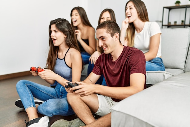 Grupo de jovens amigos sorrindo feliz jogando videogame em casa