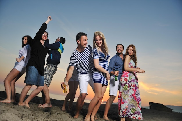 Grupo de jovens aproveita a festa de verão na praia no belo pôr do sol