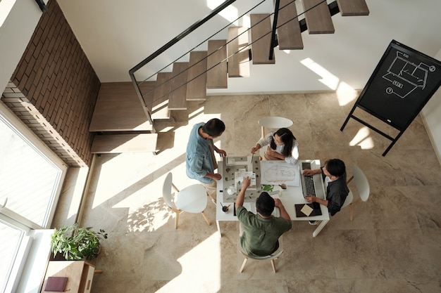 Grupo de jovens arquitetos chineses reunidos à mesa para discussão de novo projeto