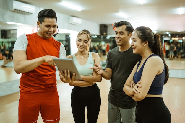 Grupo de jovens atletas e instrutor masculino usando uma almofada juntos durante o intervalo de prática da aula