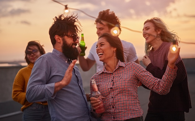 Grupo de jovens bebendo cerveja e relaxando juntos no telhado