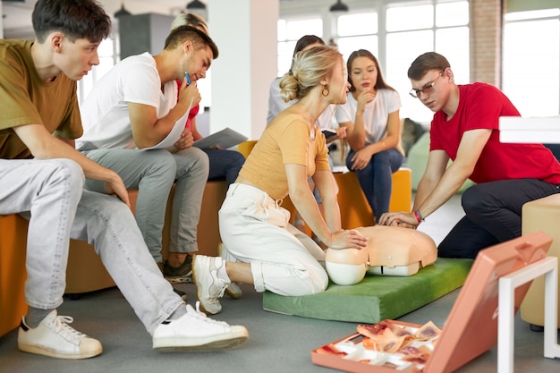 Grupo de jovens caucasianos aprendendo a salvar uma vida sentados juntos
