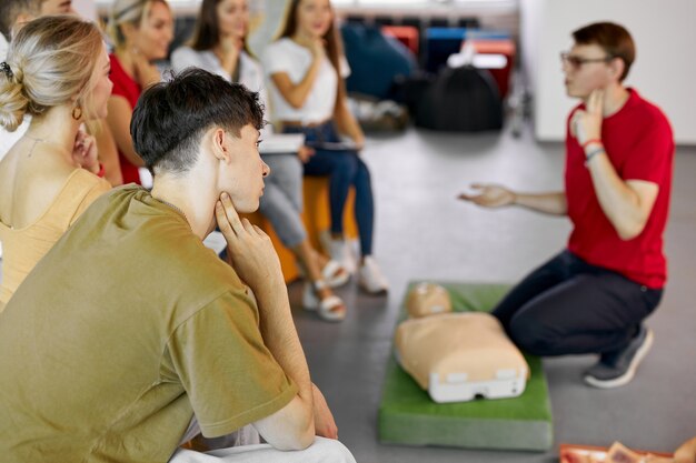 Grupo de jovens caucasianos aprendendo a salvar uma vida sentados juntos