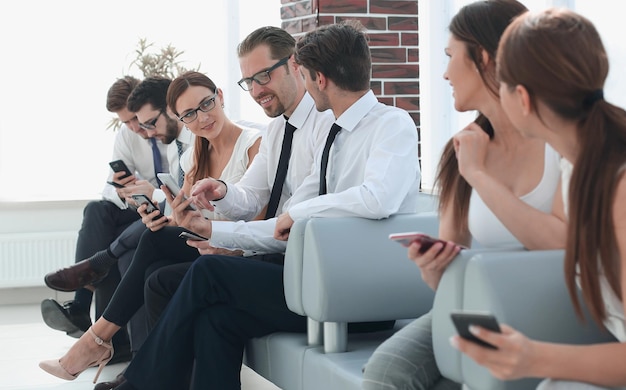 Grupo de jovens com gadgets sentados na recepção do escritóriophoto com espaço de cópia