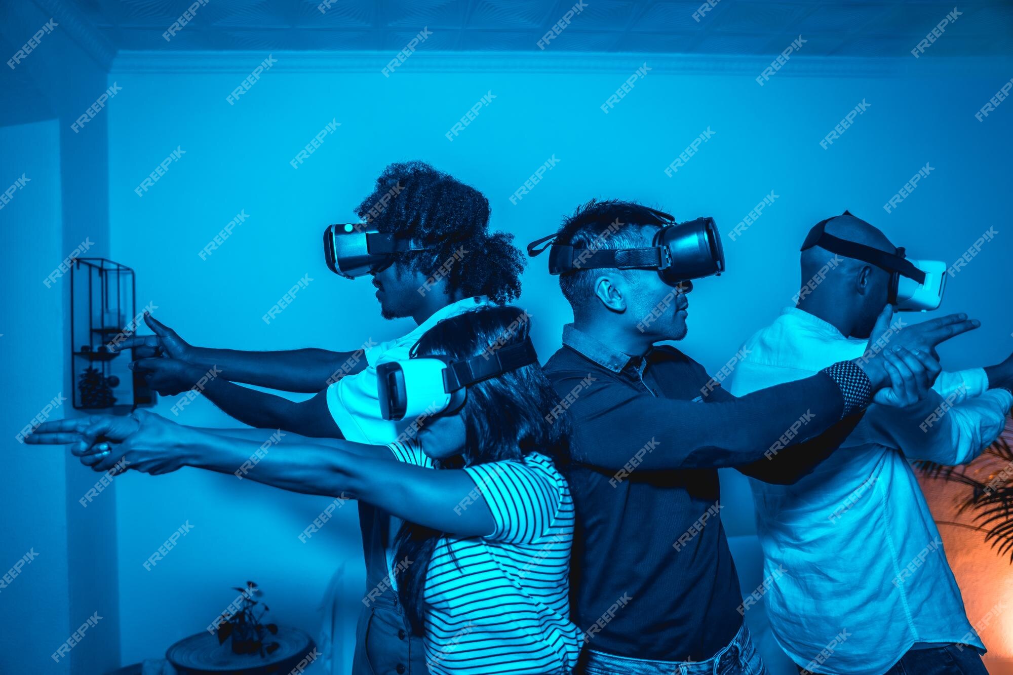 Grupo de jovens com óculos vr em um jogo de realidade virtual em uma luz  azul mirando com armas futuristas ou conceito de tecnologia científica