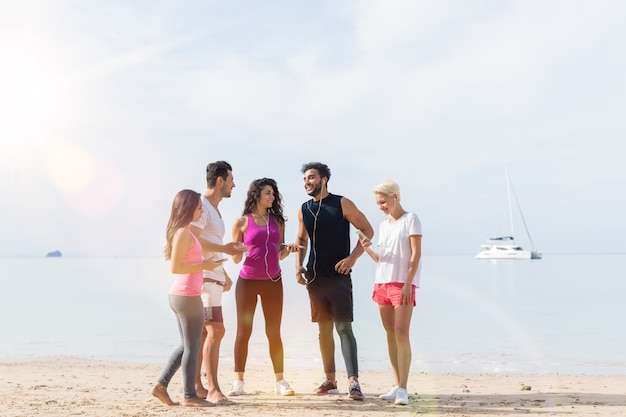 Grupo de jovens corredores na praia falando de telefones móveis de espera